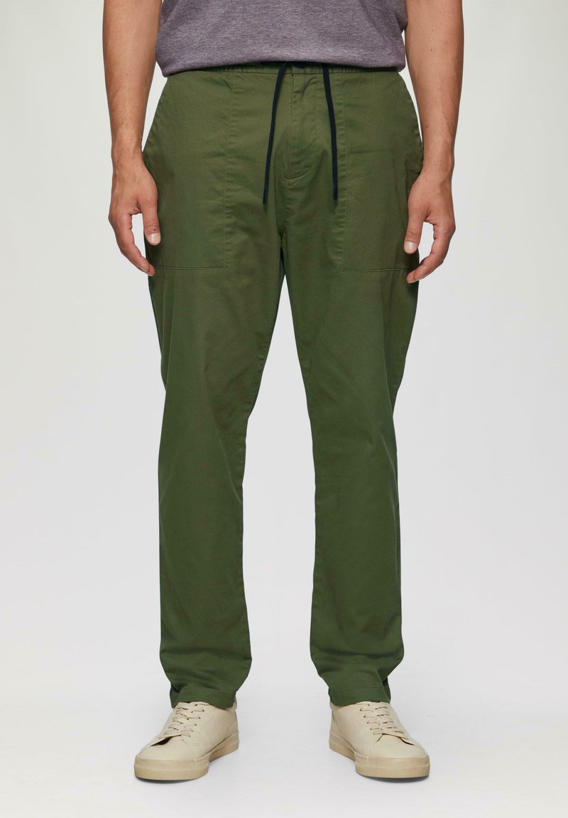 Grüne, leichte Hosen mit einem Kordelzug an der Taille, seitlichen Taschen und geradem Bein, kombiniert mit beigen Sneakers.