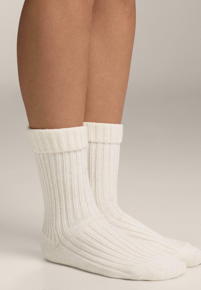 Hvide ribbede sokker med en tyk manchet og blød tekstur, designet til komfort med en glat, sømløs tå.