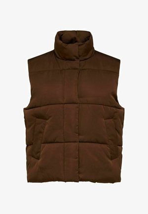 Chaleco acolchado marrón sobre un suéter ligero, combinado con pantalones de pierna ancha crema con rayas y tacones marrones puntiagudos. Texturas suaves y un look en capas.
