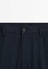 Mörkblå byxor i texturerad tyg med ett fiskbensmönster, med knappstängning och bältesslingor.