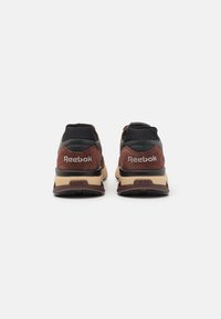 Tenisky Reebok s čiernou sieťovinou a hnedým semišovým zvrškom, béžovou medzipodrážkou, textúrovanou gumovou podrážkou a vyšitým logom na päte.