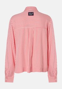 Red and white striped long-sleeve shirt with a back yoke design, buttoned cuffs, and a stitched label at the neckline. Lightweight fabric.