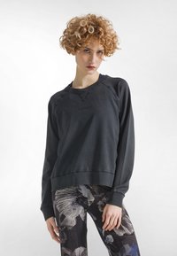 Felpa grigio scuro con scollo rotondo e maniche raglan lunghe. Texture morbida, con un logo sottile in rilievo sul davanti.