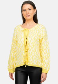 Geel geblokte trui met een v-hals, een trekkoord aan de voorkant en lange mouwen. Gemaakt van gebreide stof, met een losse pasvorm en een textuurpatroon.