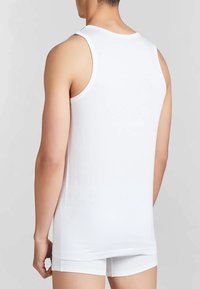 Top in cotone bianco senza maniche con scollatura rotonda, grandi aperture per le braccia e cuciture piatte. Il tessuto appare liscio e aderente, senza motivi visibili.