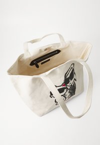 Beige auduma somiņa ar melniem un sarkanajiem varoņiem. Iekšpusē ir rāvējslēdzēja kabata, mīksts tekstūra un pagarinātas siksnas.