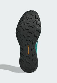 Suola di scarpa nera in gomma con un motivo di battistrada testurizzato per la trazione. Presenta dettagli color teal e un logo Continental in arancione.