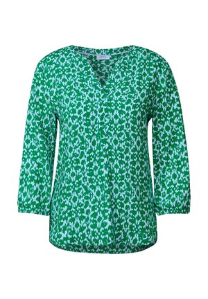 Blouse verte présentant un décolleté en V, des manches trois-quarts et un motif abstrait blanc sur l'ensemble. Tissu lisse avec une coupe décontractée.