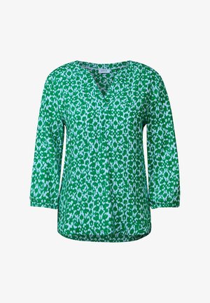 Blouse verte présentant un décolleté en V, des manches trois-quarts et un motif abstrait blanc sur l'ensemble. Tissu lisse avec une coupe décontractée.