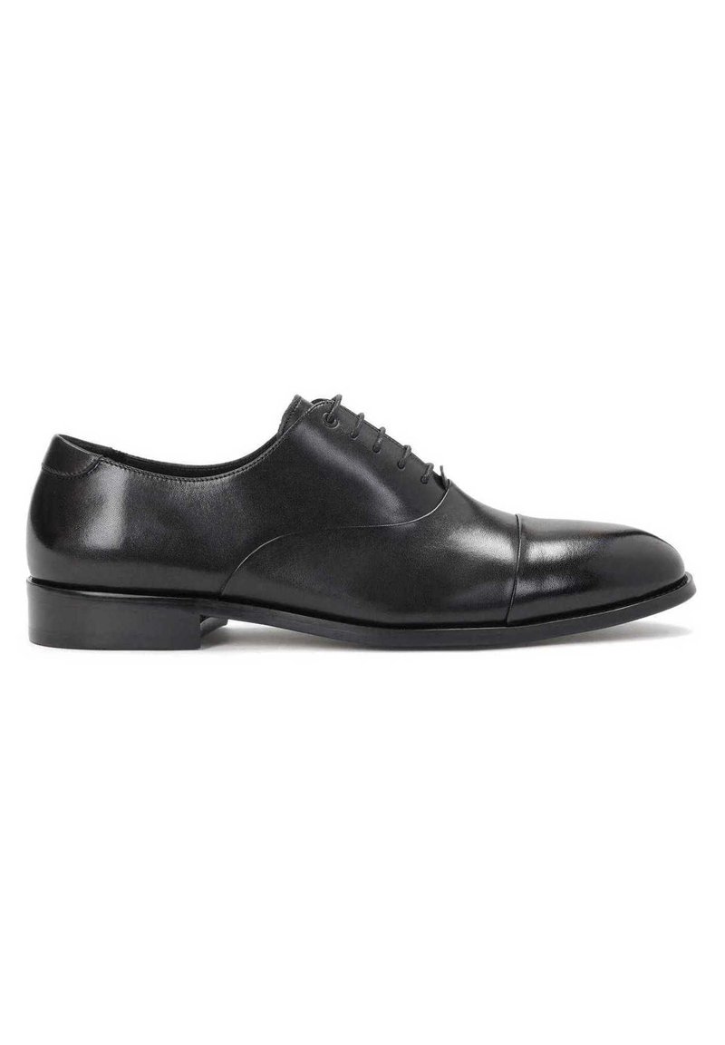 Chaussure Oxford pour homme en cuir noir avec laçage fermé, bout à capuchon, talon bas et finition lisse et polie sur fond blanc.