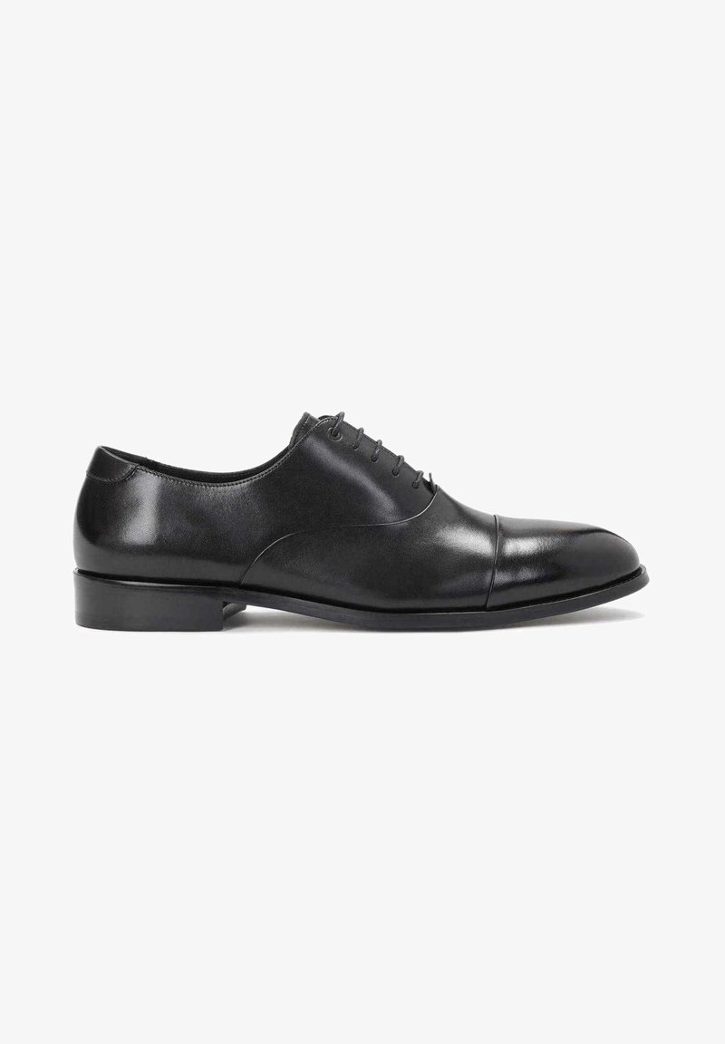 Chaussure Oxford pour homme en cuir noir avec laçage fermé, bout à capuchon, talon bas et finition lisse et polie sur fond blanc.