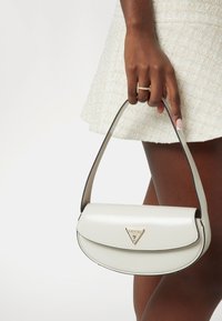 Borsa a mano in pelle sintetica bianca con forma curva, bordi neri e dettagli in metallo dorato, caratterizzata da un logo triangolare sul davanti.