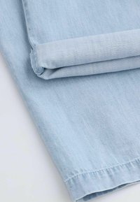 Jasnoniebieska, zwinięta tkanina deninowa o gładkiej fakturze z delikatnymi pionowymi liniami i starannie wykończonymi krawędziami. Krawędzie są starannie wykończone.