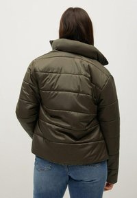 Padded olive green jacket featuring a high collar, horizontal quilted design, and a slightly cropped silhouette. Smooth texture and lightweight.