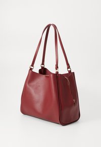 Borsa tote in ecopelle rossa con superficie liscia, tasca con zip e manici doppi. Presenta una forma arrotondata con minimi dettagli hardware.