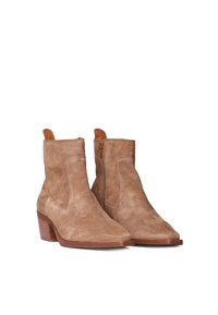 Botines de ante beige con puntera afilada y un pequeño tacón apilado. Cuentan con una cremallera lateral y un borde superior reforzado para mayor estructura.