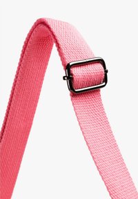 Sangle en tissu rose tissé ajustée à travers une boucle rectangulaire en métal noir sur un fond blanc.