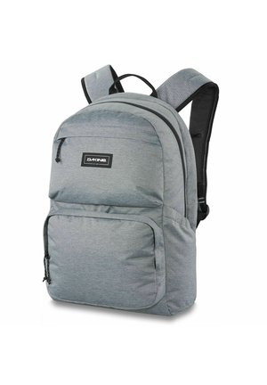 Sac à dos en tissu gris avec des bretelles rembourrées, une poche zippée à l'avant et un compartiment principal ; présente une surface texturée et un détail de logo de marque.