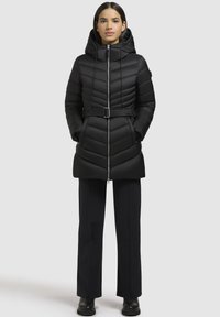 Sort puffetjakke med en tætsiddende talje, hætte og lynlås. Har chevron-quiltet tekstur, sidelommer og bælte-design.