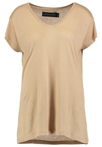 T-shirt beige a maniche corte con scollo a V, realizzato in tessuto morbido, caratterizzato da una vestibilità comoda e dettagli di cucitura sottili. L'etichetta riporta "NEVER DENIM."