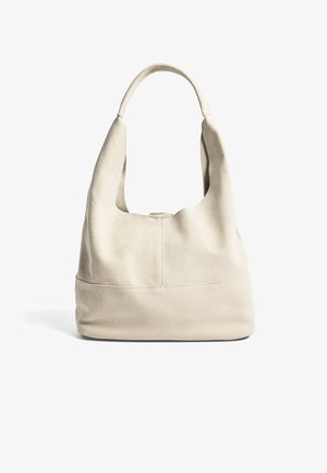 Beige nubukist hobo kott, millel on lai pehme kä handle ja ümar kuju. Omab tasast põhja ja õrna õmblust esiküljel.