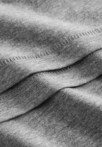 Tela de algodón gris con una textura suave, que muestra pliegues curvados y detalles de costura visibles a lo largo de las costuras.