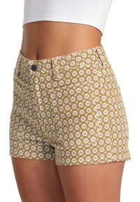 Musterhafte Shorts mit floralem Design in Weiß und Grün auf braunem Hintergrund, mit enger Passform, Gürtelschlaufen und Fronttaschen.