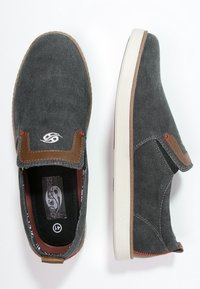 Baskets grises à enfiler en toile avec des accents en cuir marron, une semelle en caoutchouc blanc et des coutures rouges discrètes. Logo sur le côté.