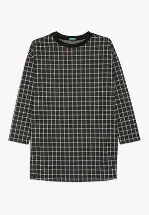 Camiseta negra de manga larga con patrón de cuadrícula blanca y cuello redondo, mostrada extendida sobre un fondo blanco.