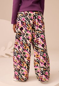Colorful leopard-print wide-leg pants featuring shades of pink, green, and brown, made of soft fabric with a relaxed fit.