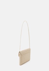 Sac d'épaule beige en tissu tissé avec un rabat pliant et une fine chaîne en métal comme bandoulière. Présente une surface texturée et une forme rectangulaire compacte.