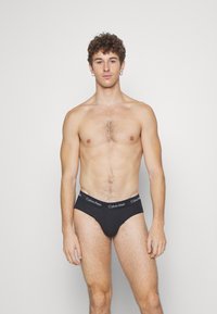 Schwarze Baumwollslips mit einem Logo-Bund, minimalistischen Design, elastischem Material und enganliegender Form. Glatte Textur mit klassischem Schnitt.