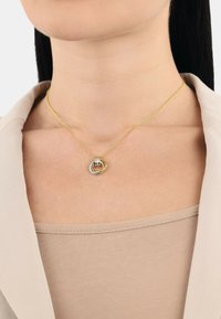 Guldhalsband med sammanlänkade silver- och guldringar i mitten. Slät metallfinish med en känslig textur.