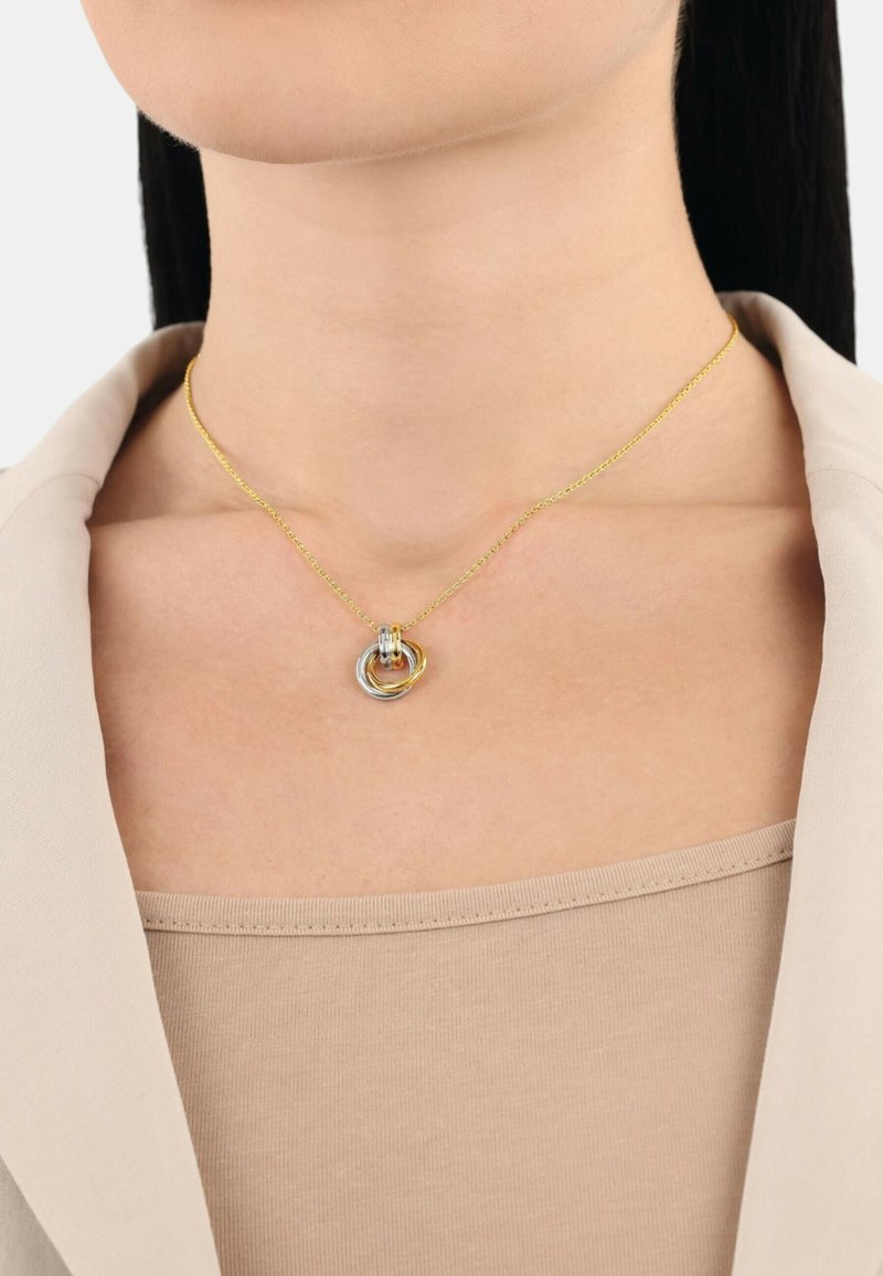 Guldhalsband med sammanlänkade silver- och guldringar i mitten. Slät metallfinish med en känslig textur.