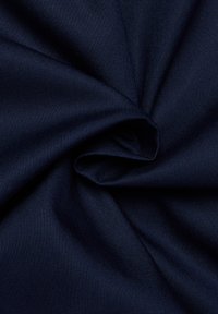 Tessuto blu scuro attorcigliato in una spirale stretta, evidenziando la trama intrecciata e la superficie liscia del materiale.