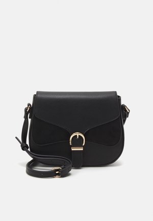 Sac bandoulière noir avec rabat et détail de boucle dorée, sangle réglable et bords inférieurs incurvés, posé sur un fond clair uni.