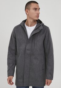 Grauer Kapuzenmantel aus wollähnlichem Stoff. Verfügt über eine Reißverschlusstasche, Druckknöpfe und eine lockere Passform mit langen Ärmeln.