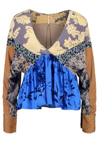 Pestrobarevná blůza s dlouhým rukávem a výstřihem do V, zdobená květinovými vzory, volány a různorodou texturou látek v modré, žluté a hnědé barvě.