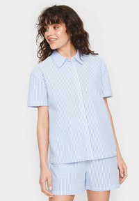 Camicia con maniche corte e pantaloni abbinati a righe verticali azzurre e bianche, realizzati in un tessuto leggero e con una texture liscia.