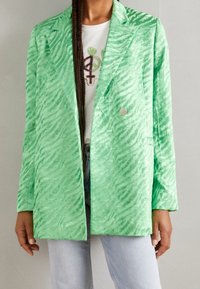 Blazer de estampado a rayas verde en tejido ligero y texturizado; presenta un collar con muesca y un cierre de un solo botón plateado.