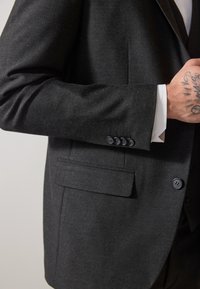 Schwarze maßgeschneiderte Sakko mit strukturierter Oberfläche, ausgestattet mit einer einzelnen Brusttasche, einem Vier-Knopf-Manschette und Reverskragen.