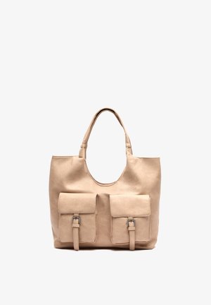 Beige läder tote-väska med två framfickor, justerbara remmar och en mjuk, texturerad yta. Enkel, rundad design med minimal hårdvara.