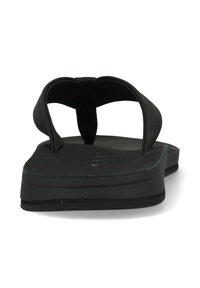 Zwarte slippers met een strak ontwerp, een platte zool, rubberen banden en een gepersonaliseerde voetbed voor grip.