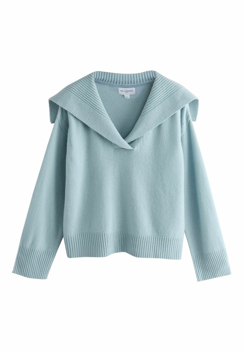 Gaiši zilas krāsas džemperis no mīksta auduma, ar lielu V veida kakla izgriezumu un ribotu aproci un apakšu. Garas piedurknes ar nolaistām pleciem.