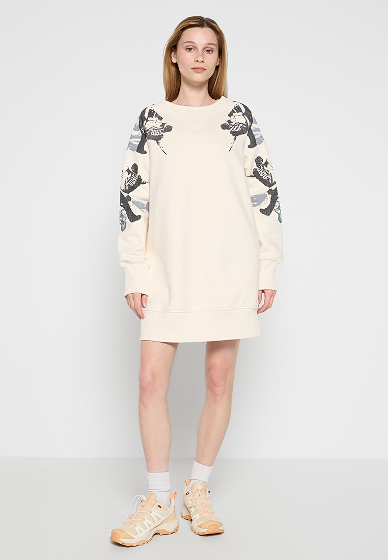 Cremfarbendes Sweatshirtkleid mit langen Ärmeln, das ein grafisches Design in Schwarz und Grau auf den Ärmeln aufweist. Rundhalsausschnitt, weicher Stoff.