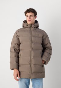 Pufferjack in gedempt bruin, met een ritssluiting, capuchon en zijzakken. Soepele textuur met een gewatteerd design en subtiele branding.