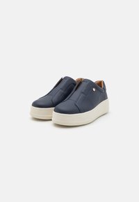 Marineblå slip-on sko med teksturert skinnmateriale, kontrasterende hvit såle, og subtile designdetaljer med en glatt overflate.