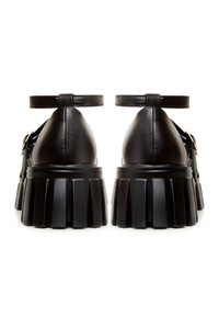 Pantofi cu platformă din piele neagră, cu vârf rotunjit, curele de gleznă și o talpă texturată, cu profil ușor în relief. Design simplu, cu detalii hardware minime.