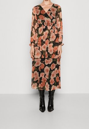 Robe maxi florale avec un fond noir et des roses roses, manches longues, décolleté en V et taille froncée ; associée à des bottes noires jusqu'aux genoux.
