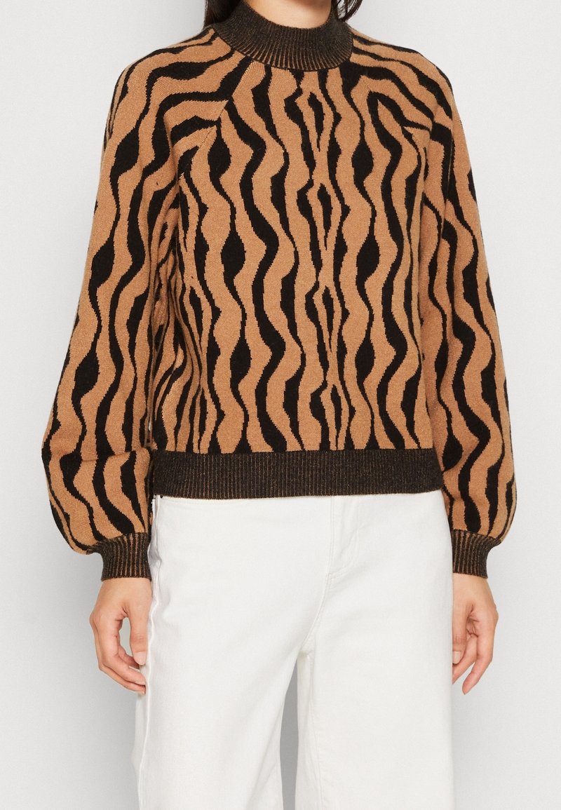 Brun och svart tröja med vågmönster, utrustad med ribbad krage och manschetter, med avslappnad passform och något puffärmar.